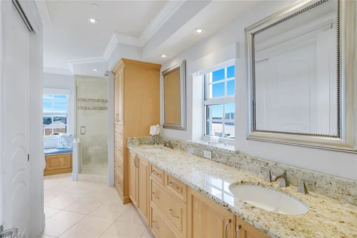Full bath featuring ornamental molding, a stall shower, double vanity, tile patterned flooring, and recessed lighting.  Walk in his/her closet across from double vanity.