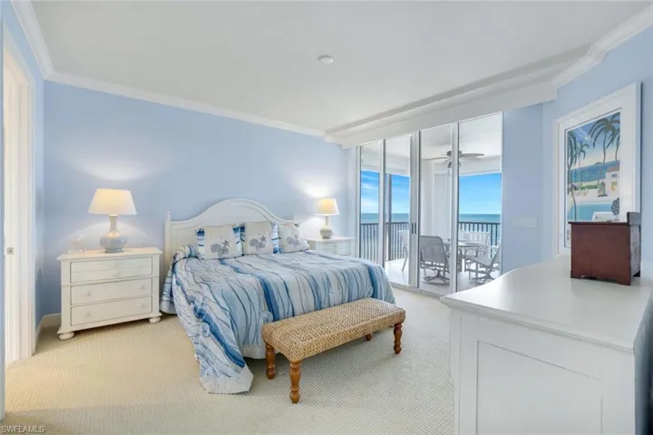Master bedroom featuring light carpet, crown molding, and access to exterior lanai.  Window coverings are electronic.