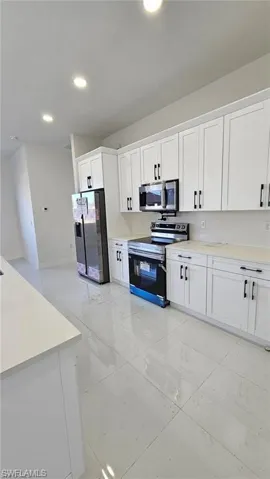 Kitchen featuring appliances with stainless steel finishes and white cabinets