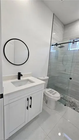 Bathroom with vanity, toilet, and a shower with door