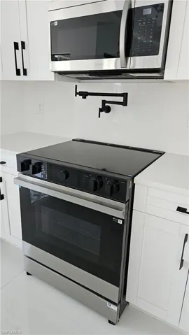 Kitchen featuring white cabinetry and appliances with stainless steel finishes