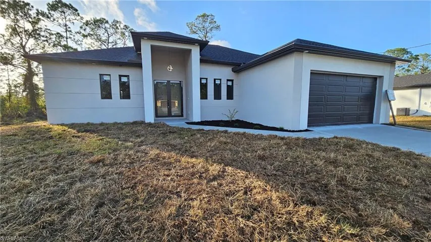 View of front of house featuring cooling unit, a garage, and a front yard