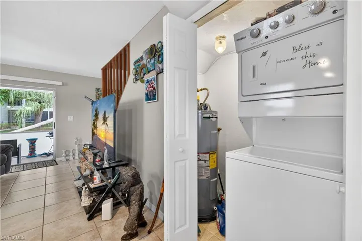 Compact laundry area featuring a stacked washer and dryer unit, water heater, and bi-fold door