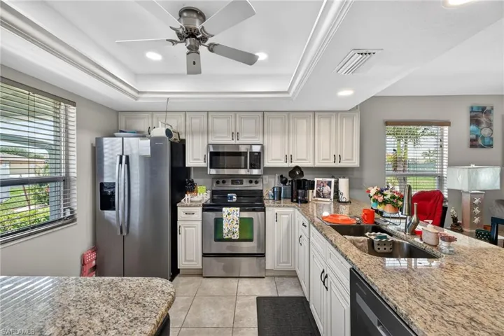 Kitchen featuring light-toned cabinetry, stainless steel appliances, and granite countertops