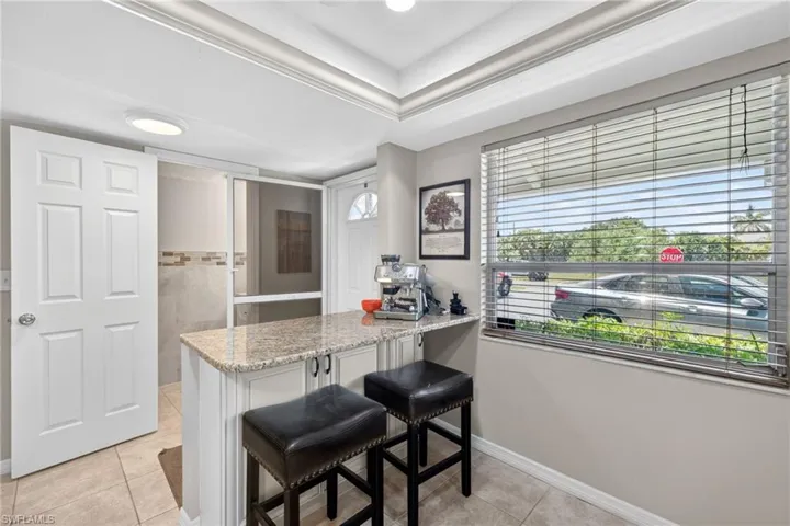 Kitchenette featuring a granite-look countertop, white cabinetry with dark hardware, and recessed lighting