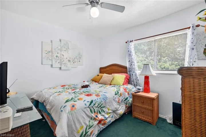 Bedroom featuring a ceiling fan with integrated lighting, a window with blinds, and green carpeting