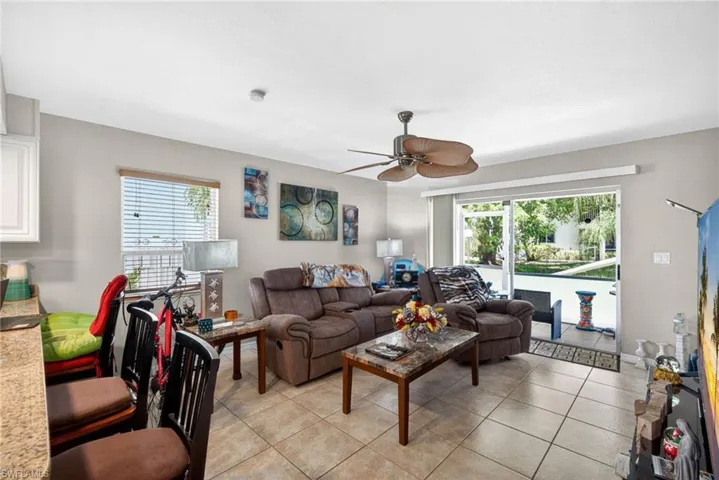 Spacious living area featuring tile flooring, a ceiling fan, and sliding glass doors opening to an outdoor patio with water access