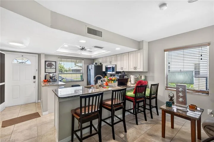 Kitchen featuring a granite-topped island with seating, white cabinetry, and stainless steel appliances