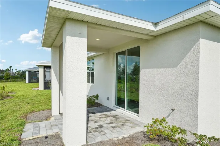 View of exterior entry featuring a yard and a patio area