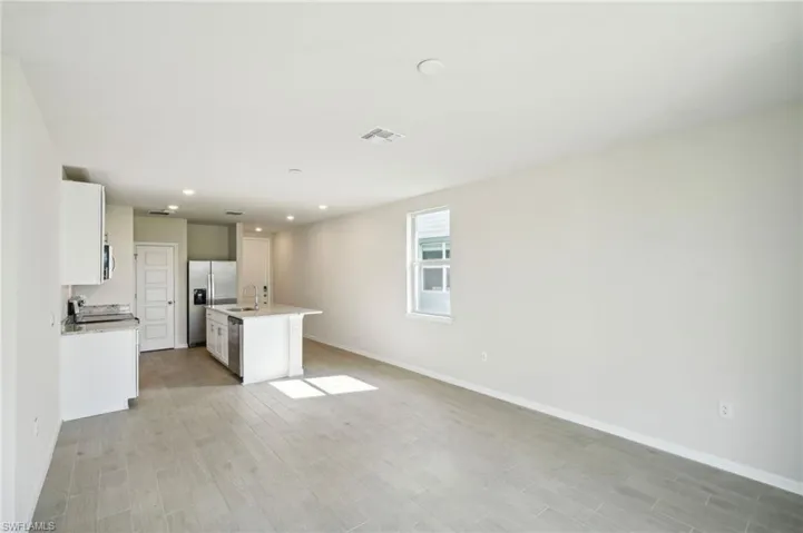 Kitchen with white cabinetry, an island with sink, stainless steel appliances, light hardwood / wood-style flooring, and sink