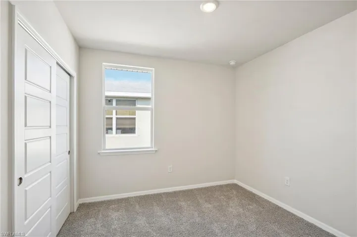 Unfurnished bedroom with light colored carpet and a closet
