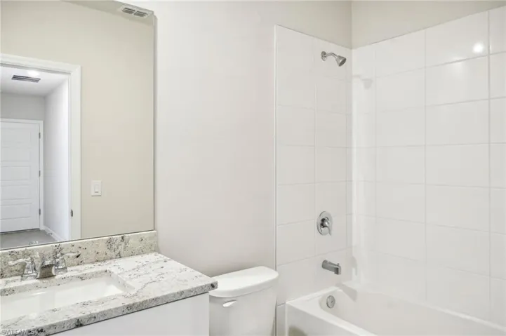Full bathroom with tiled shower / bath combo, vanity, and toilet