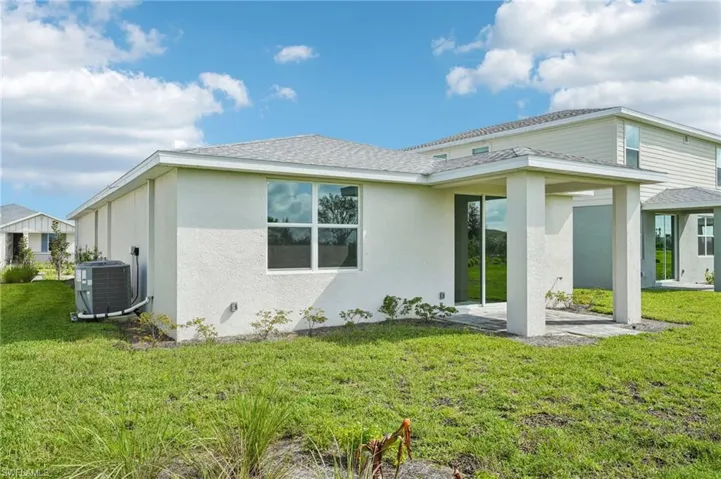 Rear view of house with a lawn, a patio, and central AC unit