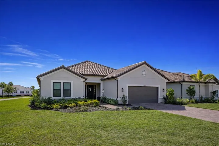 Mediterranean / spanish home featuring a front lawn, a tiled roof, and a garage