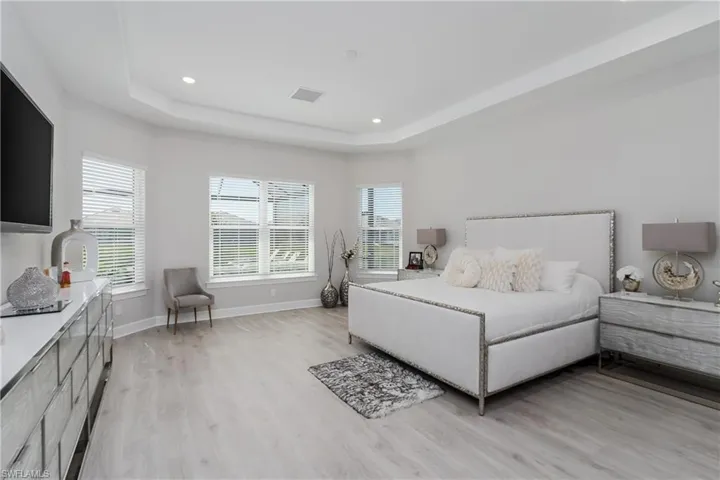 Bedroom featuring light wood-style flooring, a raised ceiling, and recessed lighting