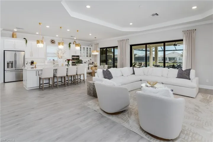Living area with a tray ceiling, light wood finished floors, recessed lighting, and crown molding