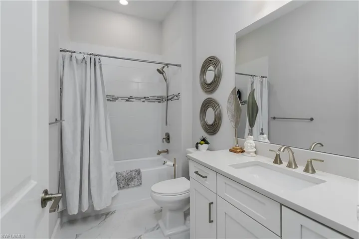 Full bath featuring vanity, shower / bath combination with curtain, and marble look tile flooring