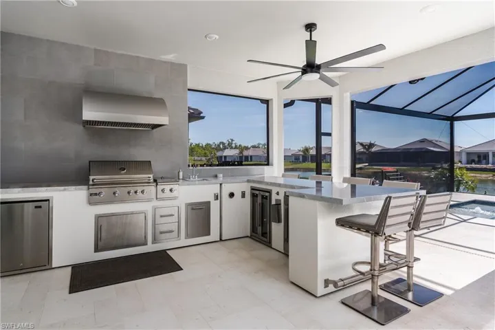 View of patio / terrace featuring area for grilling, glass enclosure, a residential view, and a ceiling fan