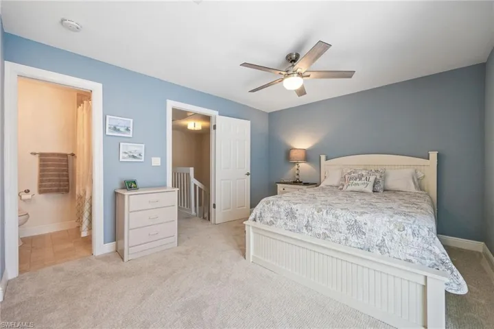 Guest bedroom with light carpet, a ceiling fan, and ensuite bathroom