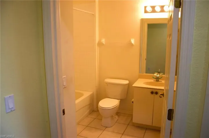 Bathroom featuring a white toilet, tile flooring, and a vanity with a circular basin sink and cabinet storage