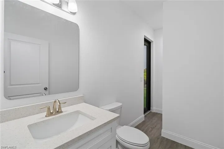 Bathroom with hardwood / wood-style floors, vanity, and toilet