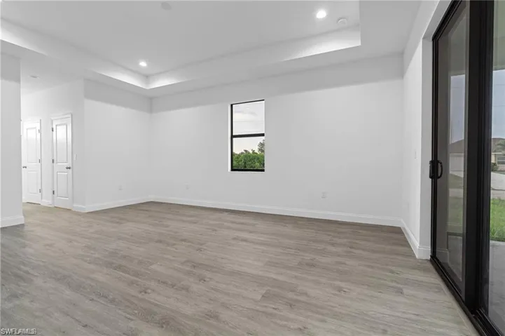 Empty room featuring light wood-type flooring and a tray ceiling