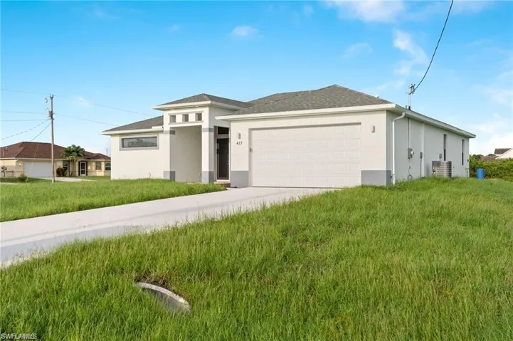 Prairie-style home featuring cooling unit, a garage, and a front lawn