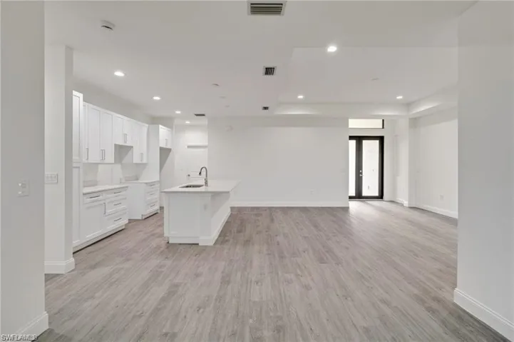 Kitchen featuring white cabinetry, light hardwood / wood-style floors, sink, and an island with sink