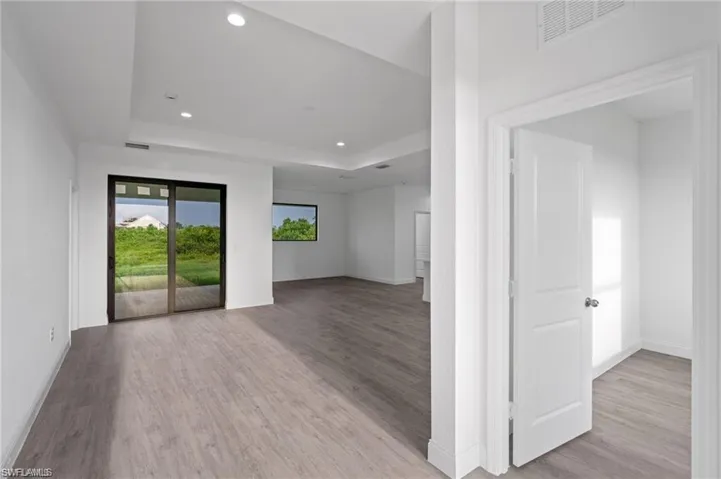 Empty room with a raised ceiling and light hardwood / wood-style flooring