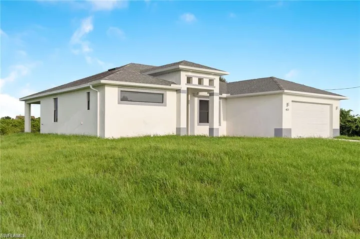 Rear view of property with a garage and a lawn