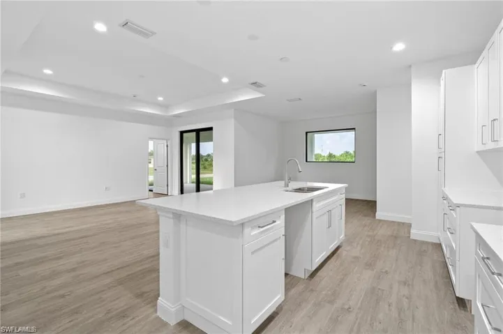 Kitchen featuring light hardwood / wood-style flooring, a healthy amount of sunlight, and a center island with sink