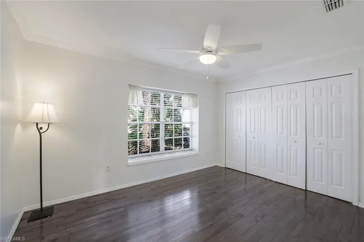 Bedroom with crown molding, wood-style flooring, ceiling fan, and a closet