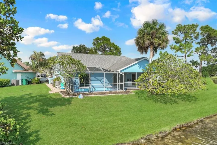 Back of house featuring a lanai and a lawn