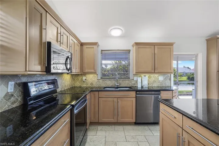 Kitchen with a wealth of natural light, dishwasher, black range with electric stovetop, and sink