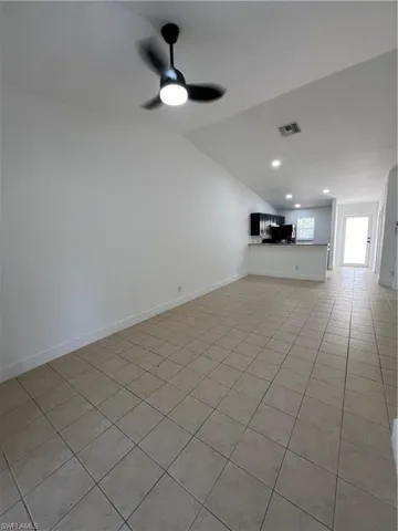 Unfurnished living room with lofted ceiling, light tile patterned floors, a ceiling fan, recessed lighting, and baseboards