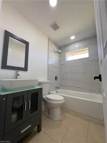 Bathroom with vanity, toilet, bathing tub / shower combination, tile patterned flooring, and recessed lighting