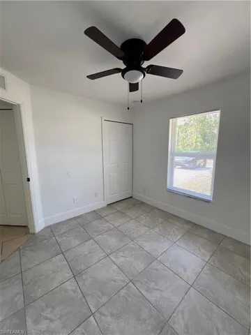 Unfurnished bedroom with tile patterned flooring, a closet, baseboards, and a ceiling fan