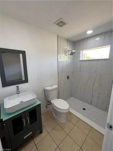 Full bathroom featuring vanity, a tile shower, toilet, and tile patterned floors