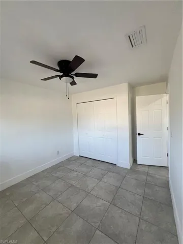 Unfurnished bedroom with baseboards, tile patterned flooring, a closet, and a ceiling fan