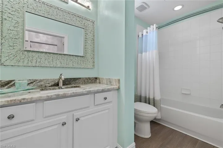 Updated guest bathroom offers granite counters, custom lighting and a tub/shower.