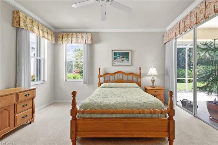 Spacious Primary Bedroom featuring baseboards, sliders to screened lanai, crown molding, and light carpet