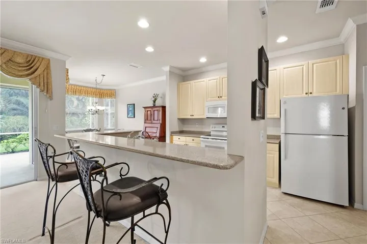 Kitchen featuring white appliances, a breakfast bar area, and crown molding