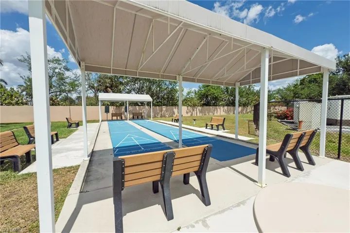 View of pool with shuffleboard, fence, and a lawn