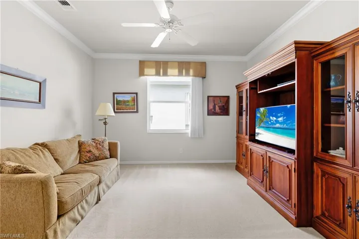 Large Den featuring crown molding, baseboards, and light carpet