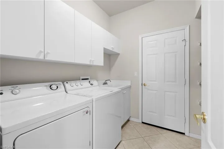 Laundry room with light tile flooring, baseboards, washer and dryer, and lots cabinet space