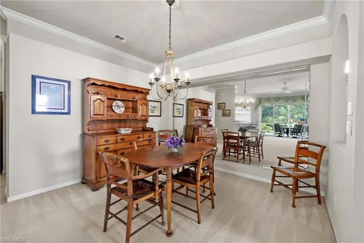 Dining room with crown molding, baseboards, a chandelier, and light carpet
