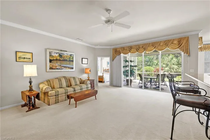 Living room with crown molding, carpet, and ceiling fan