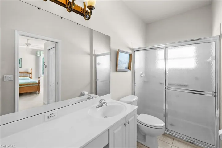Ensuite bathroom with toilet, tile floors, vanity, and a walk-in shower