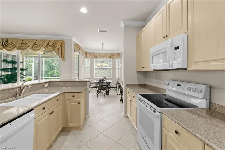 Kitchen with light appliances, crown molding, a sink, and quartz countertop.