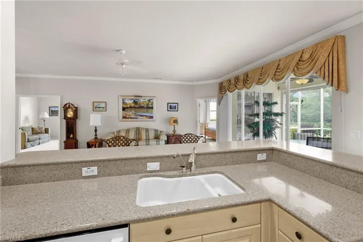 Kitchen with a sink, white dishwasher, crown molding, and light quartz countertops.